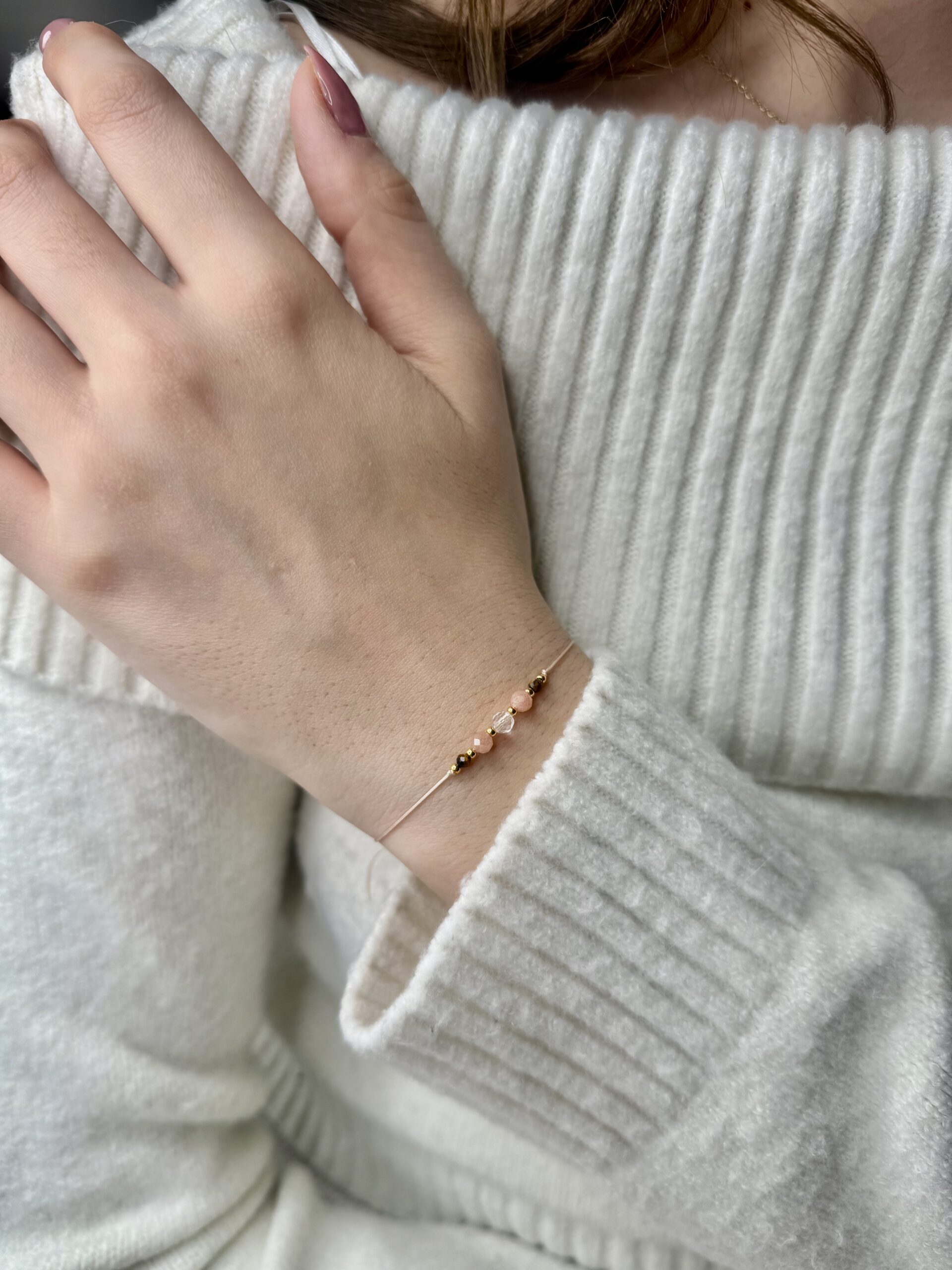 ręcznie robiona bransoletka zodiakalny lew z naturalnymi kamieniami kryształ górski, tygrysie oko i kamień słoneczny, na nadgarstku