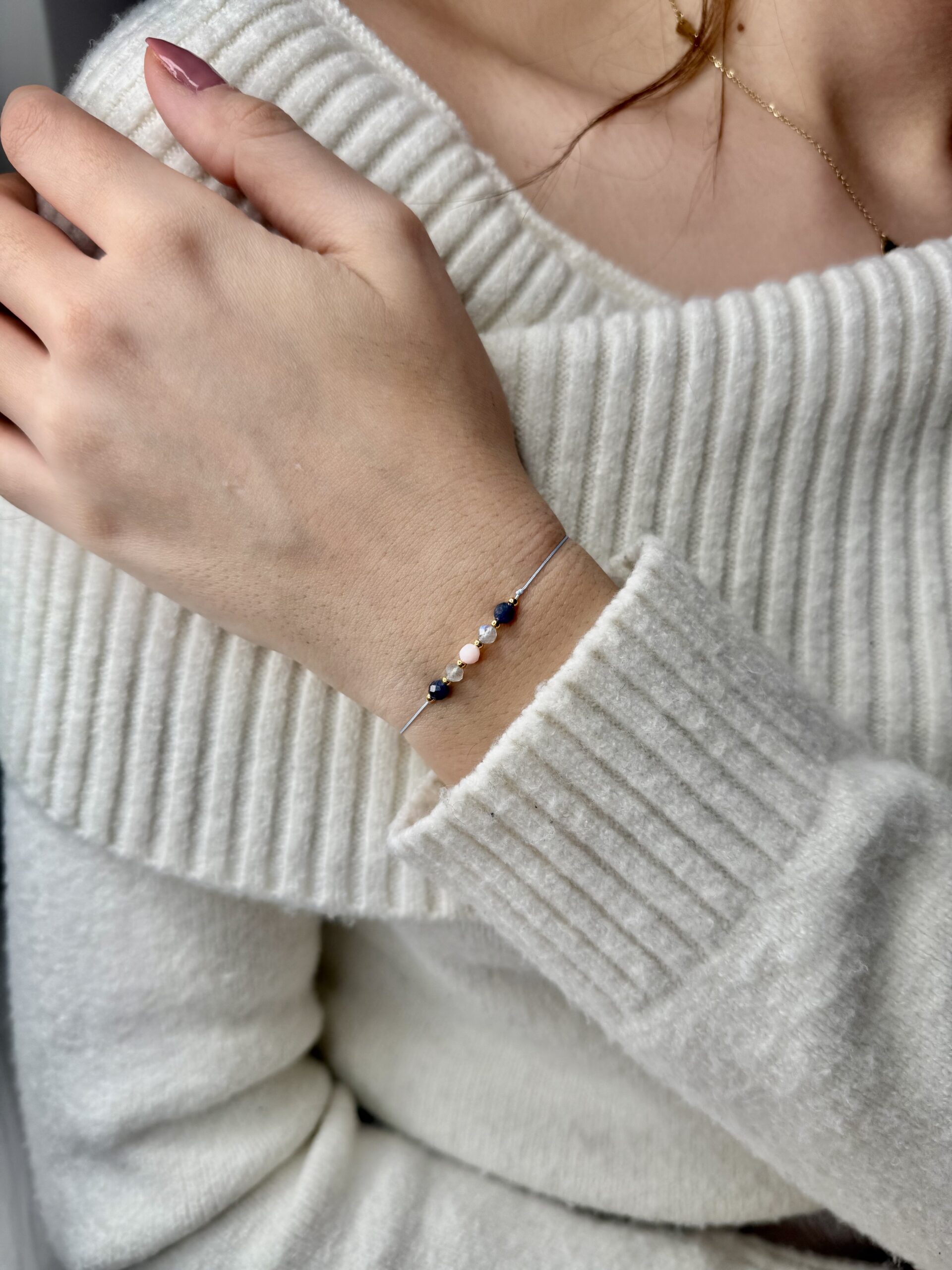 ręcznie robiona bransoletka strzelec z naturalnymi kamieniami opal różowy, labradoryt i sodalit, na nadgarstku na białym tle