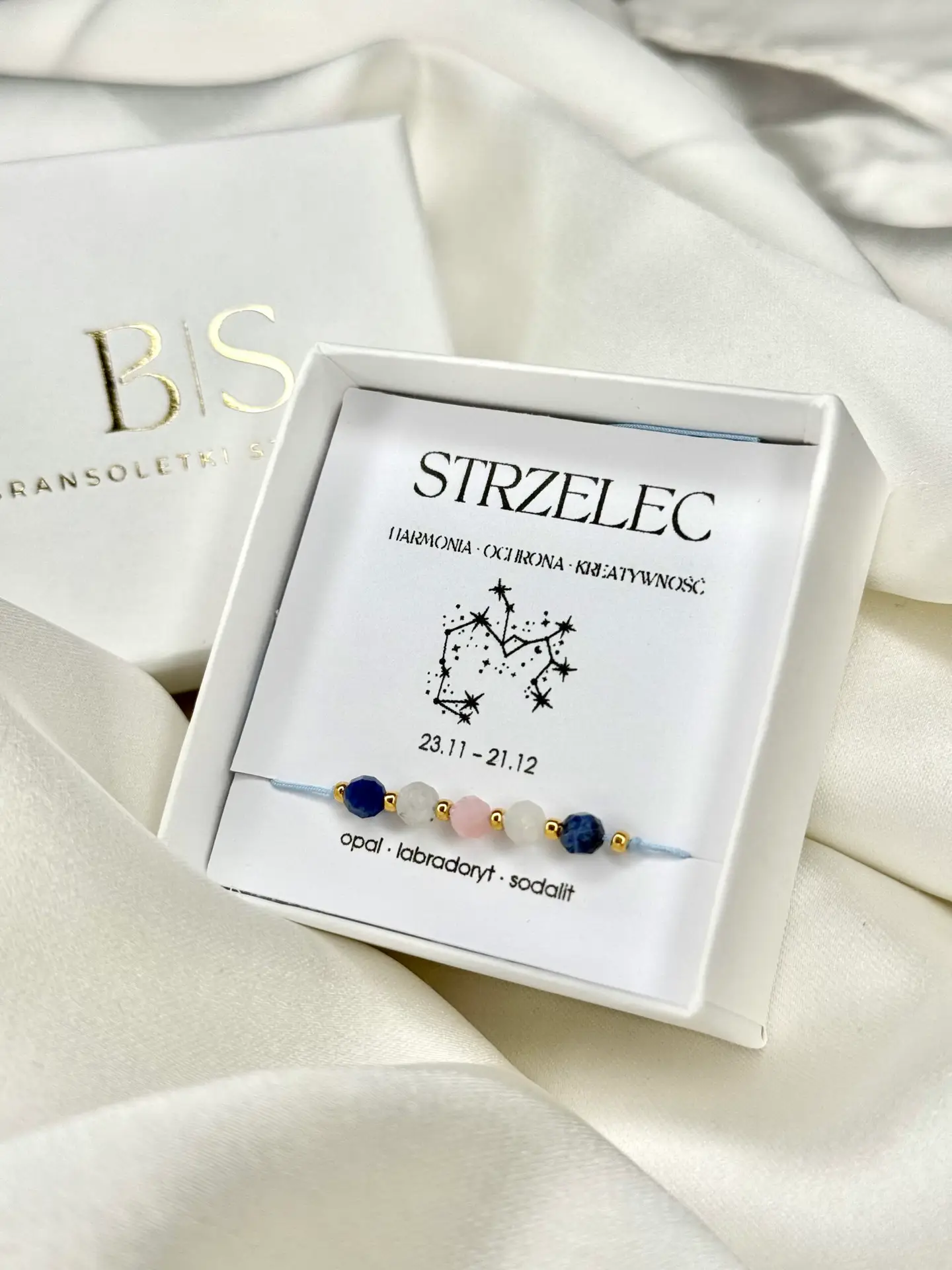 Bransoletka zodiakalna Strzelec w białym pudełku prezentowym na białym tle.