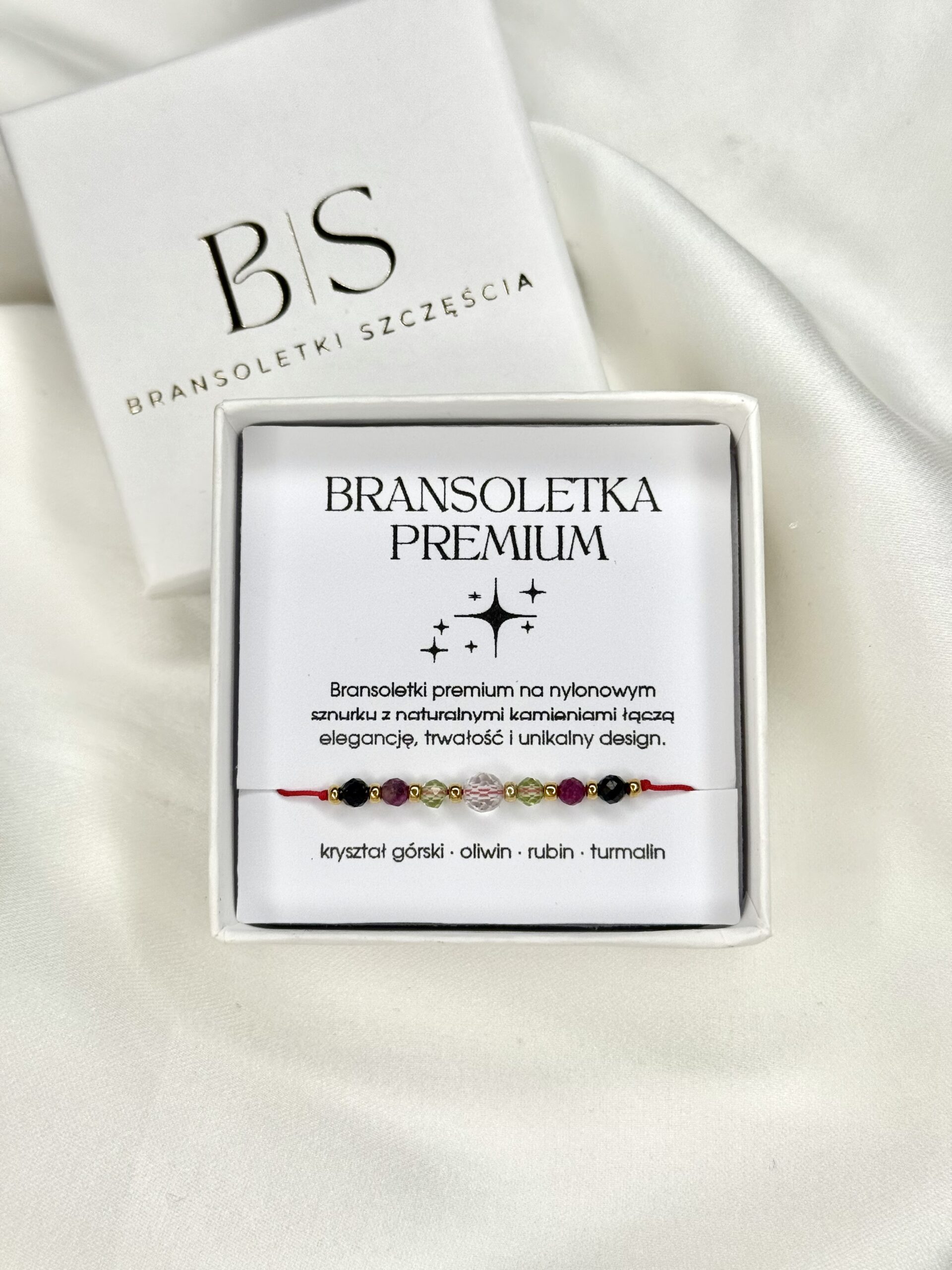 Bransoletka na czerwonym sznurku z naturalnymi kamieniami: kryształ górski, oliwin, rubin i czarny turmalin, na nadgarstku